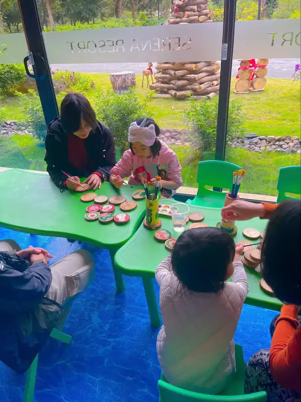 Các bé ngồi tô màu lên lát gỗ tròn trong buổi workshop thủ công cho trẻ ở Serena Kim Bôi