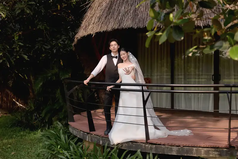 Cô dâu chú rể trên hiên gỗ trước căn nhà mái tranh trong vườn – Serena Resort Kim Bôi