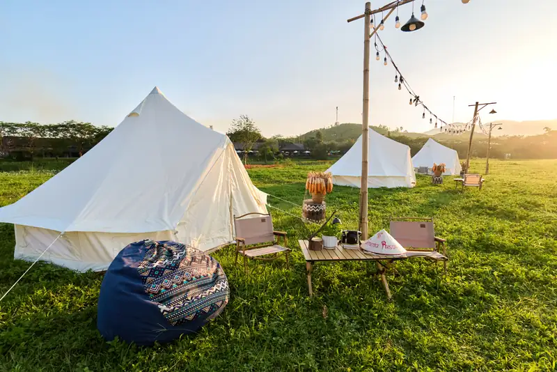 Lều chuông trắng, bàn ghế dã ngoại và dây đèn trên bãi cỏ khu Serena Camping