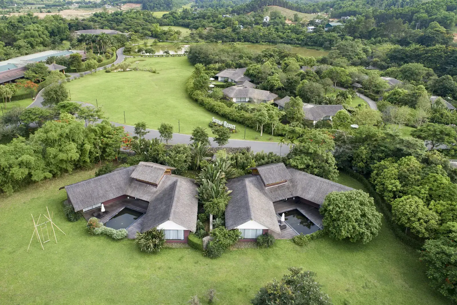 Các villa mái tranh giữa bãi cỏ và vườn cây ở Serena Resort Kim Bôi nhìn từ trên cao