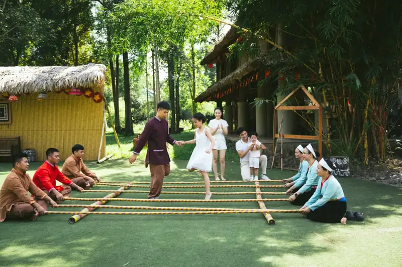 Khách thử múa sạp cùng người Mường trên bãi cỏ trước nhà sàn ở Serena Kim Bôi