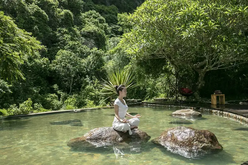 Khách ngồi thiền trên tảng đá giữa bể onsen ngoài trời ở Serena Kim Bôi