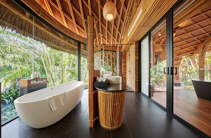 Phòng tắm Bungalow có bồn tắm trắng, chậu rửa ốp tre và vách kính