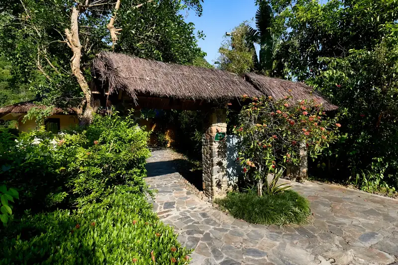 Lối đi lát đá và cổng mái tranh vào Garden Villa giữa vườn cây