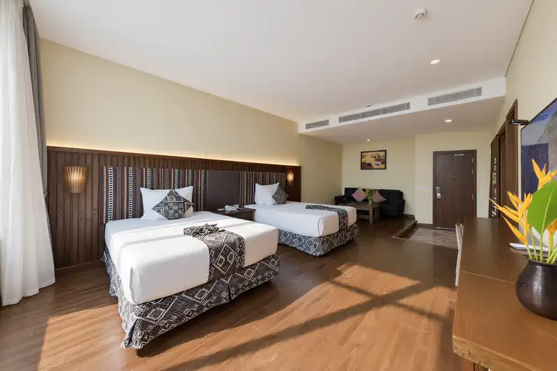 Phòng Zen House hai giường và góc sofa, đèn hắt trên vách gỗ