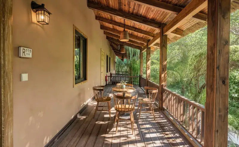 Hiên gỗ có bàn ghế trước dãy Zen Suite ở Serena Kim Bôi, nhìn ra cây xanh