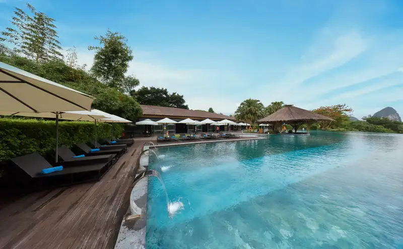 Bể bơi vô cực ngoài trời ở Serena Kim Bôi, hàng ghế nằm và mái tranh dưới núi
